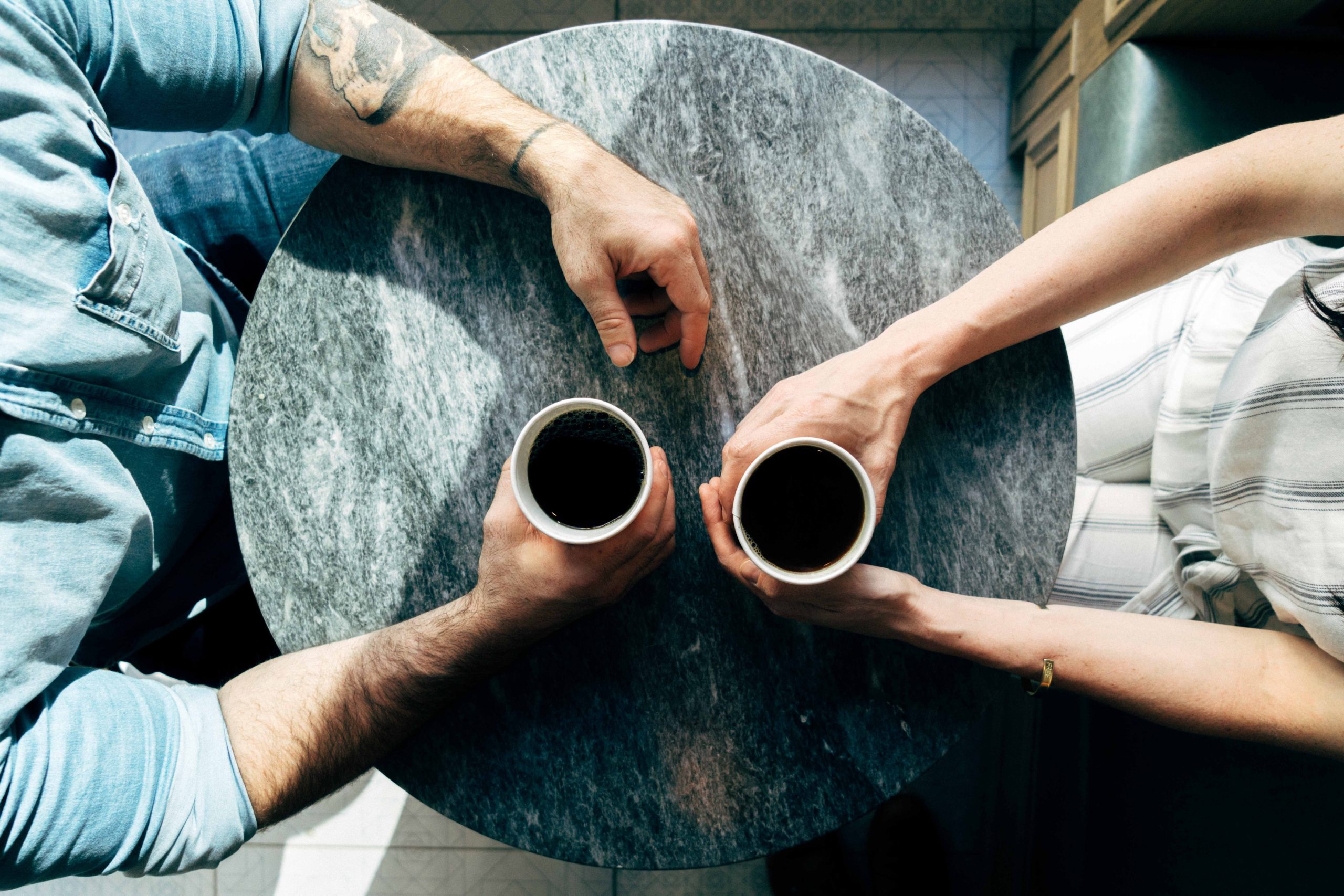 A man and woman holding cups of coffee on a table